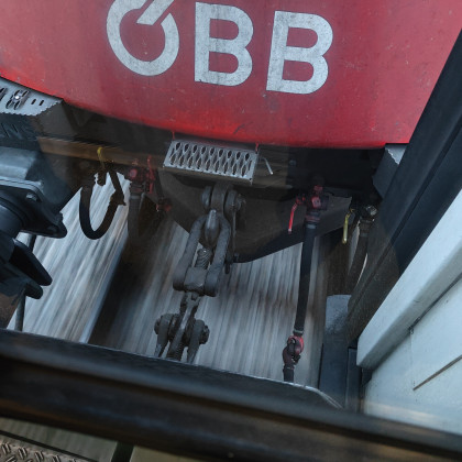 öbb lokomotiva, na katero je priklopljen hrvaški vagon, v ozadju se vidi stran brzeča tla