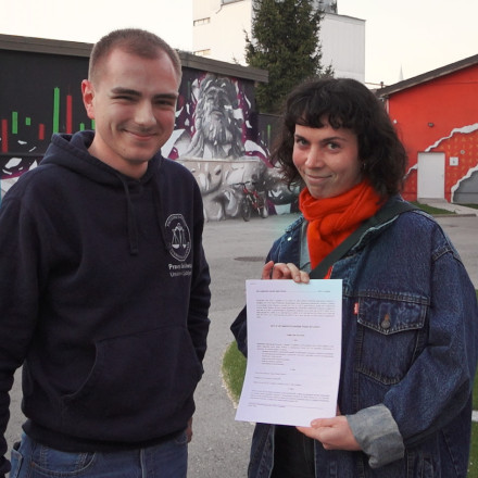 Slika prikazuje svetovalca predsesdstva ŠOU Kristijana Briškega in direktorico Radia Študent Valentino Rajaković med primopredajo spremenjenega Akta o ustanovitvi Zavoda Radia Študent, po 6. redni redni seji Študentskega zbora ŠOU.