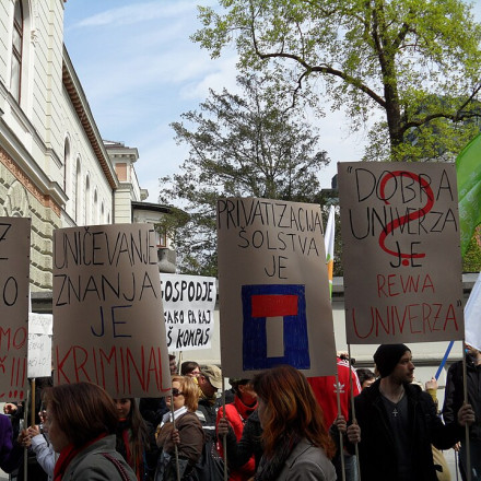 Splošna stavka javnega sektorja pred vladno palačo, aprila 2012. Na transparentih je od leve proti desni napisano "Dol z vlado ne rabimo vas več", "Uničevanje znanja je kriminal", "Politizacija šolstva je [slepa ulica]", "Dobra univerza je revna univerza?".