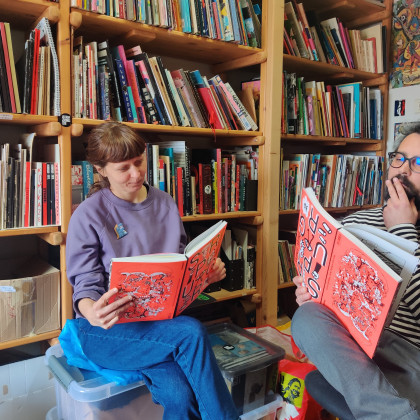 Tanja Skale in David Krančan zamišljeno prebirata izdajo Dirty Thirty v Stripburgerjevi knjižnici