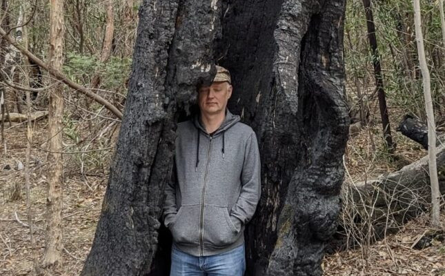 Mož stoji v razpoki mrtvega a še stoječega drevesa